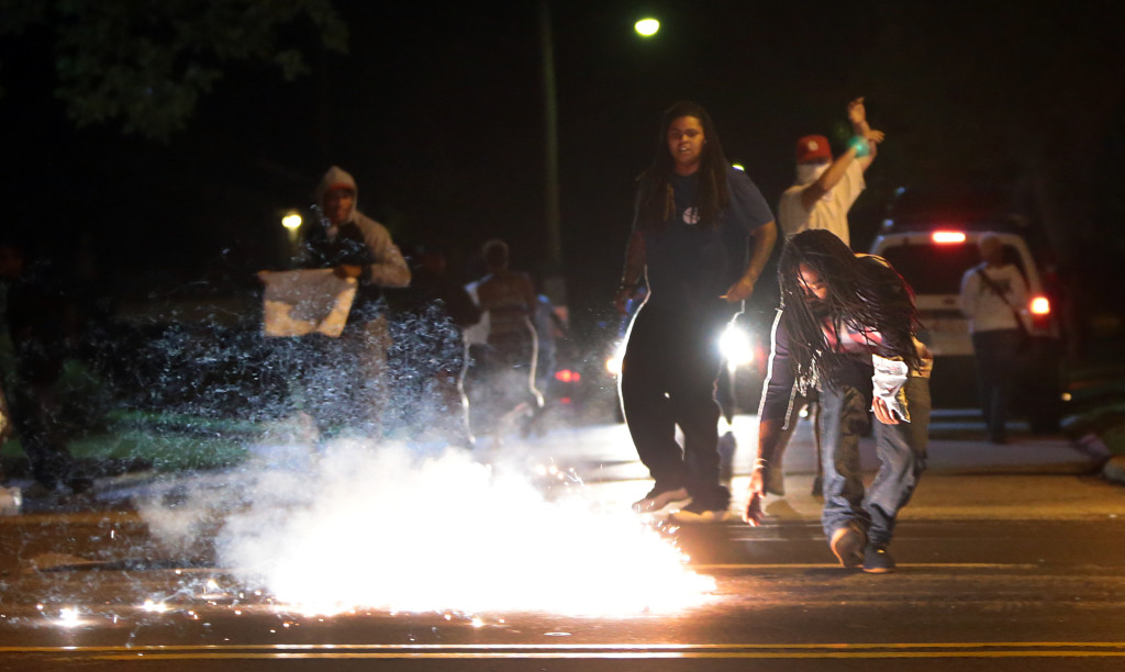 Edward Crawford reaches for the tear gas canister that has just landed nearby.