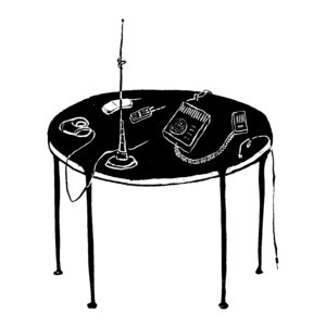 A table with an antenna, walkie talkies, and some headphones.